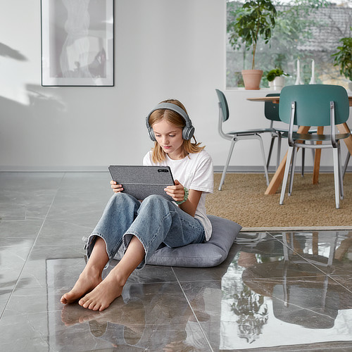 Mädchen sitzt mit Tablet in der Hand auf dem Fußboden