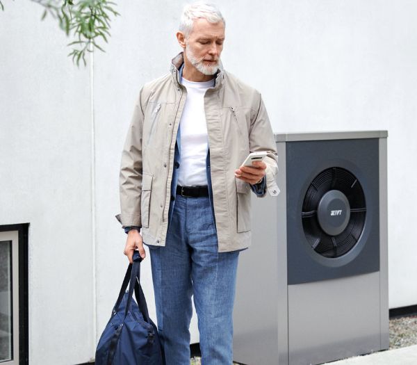 Mann mit einer Wärmepumpe im Hintergrund