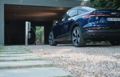 Grauer Audi steht neben einer Ladestation
