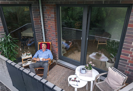 Mann sitzt auf Balkon