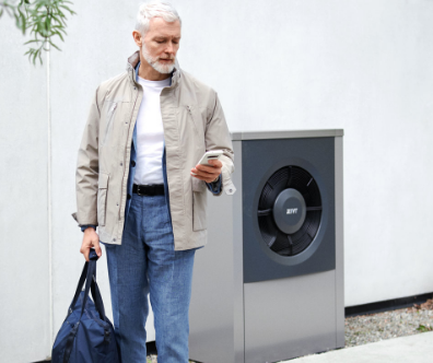 Mann mittleren Alters mit einer Wärmepumpe im Hintergrund