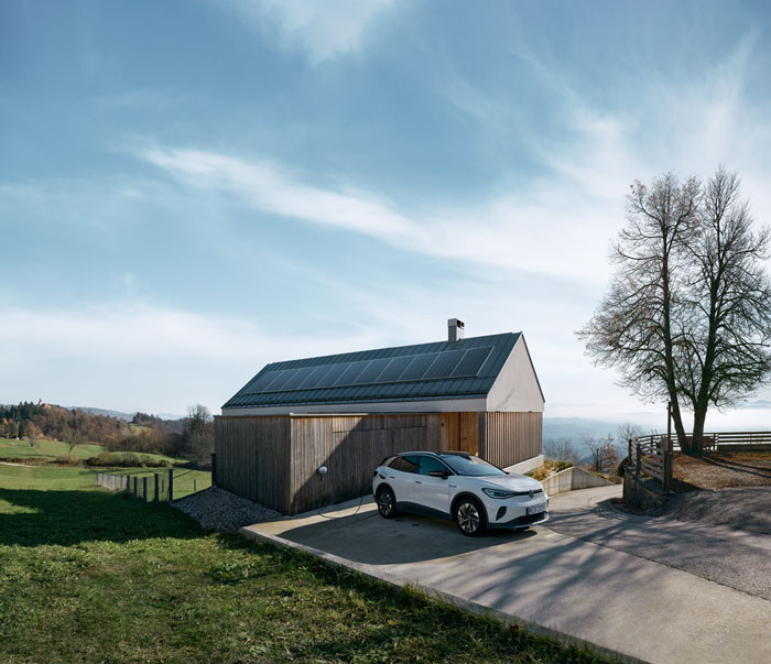 Haus mit Solaranlage auf dem Dach, davor steht ein E-Auto