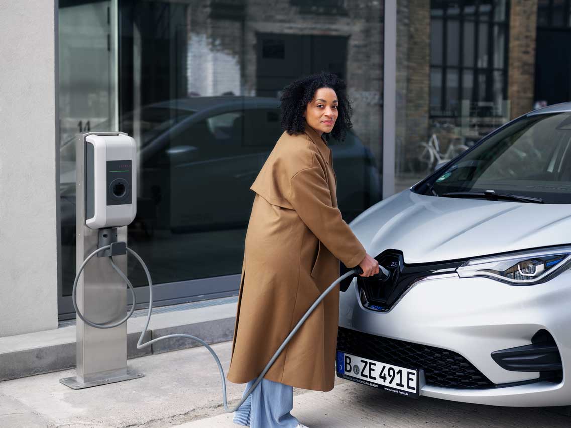 Frau steckt den Ladestecker in ihr E-Auto